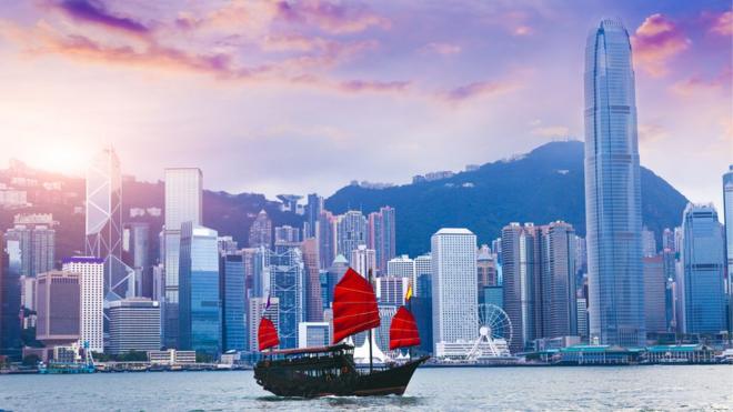 A sailboat travels past Hong Kong Victoria Harbour at sunset (stock picture)
