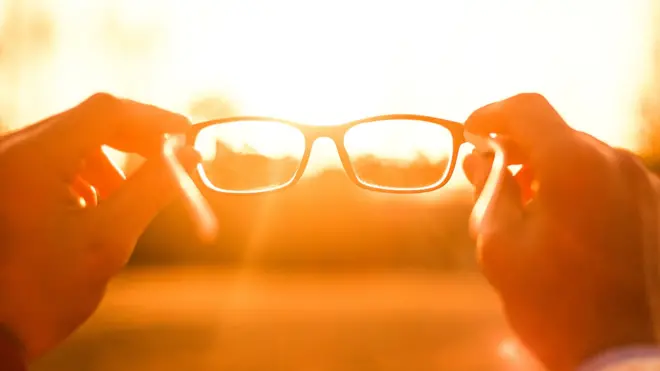 A person holding glasses against the sun