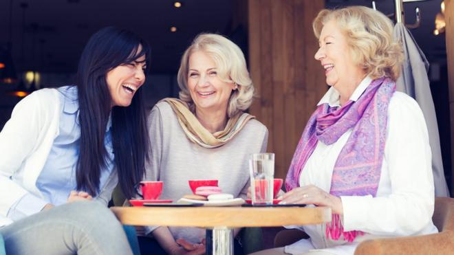 Two senior ladies and one young woman having coffee time in modern cafe