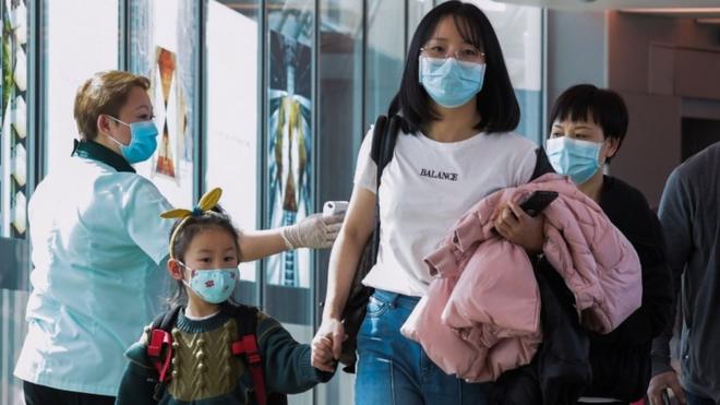 A health officer (L) screens arriving passengers from China at Changi International airport in Singapore on January 22, 2020 as authorities increased measure against coronavirus.