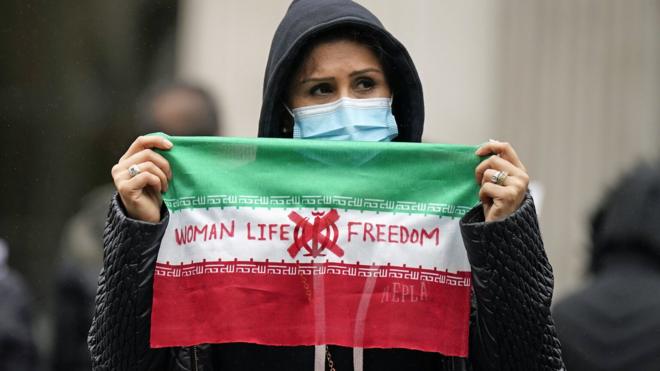 Woman holds protest sign at Trafalgar Square, London (29/10/22)