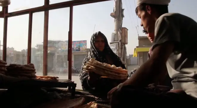 ภาพผู้หญิงถือของ ผู้ชายนั่งอยู่