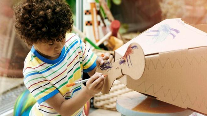 Un niño haciendo un avión de cartón
