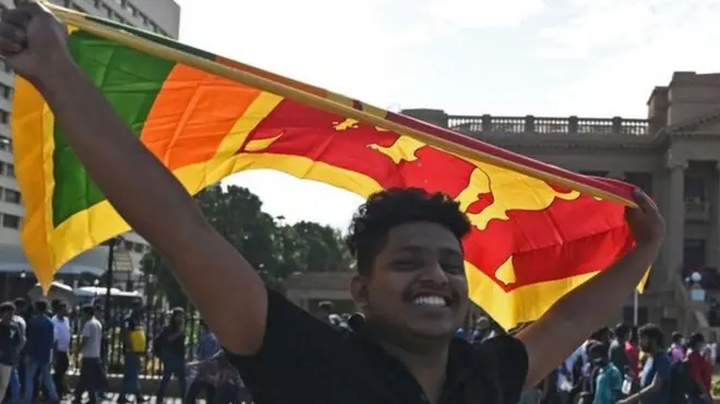 Un hombre ondea la bandera nacional de Sri Lanka frente a la secretaría presidencial en Colombo el 13 de julio de 2022.