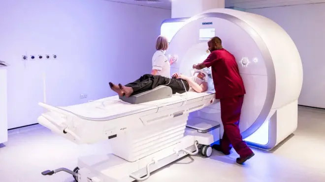 Radiology staff preparing a patient for a magnetic resonance imaging (MRI) scan of their brain