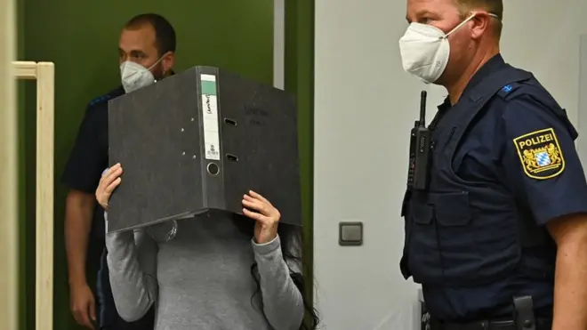 Jennifer Wenisch in court, covering her face with a folder, 13 Oct 21