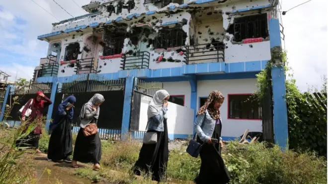 Sejumlah warga Kota Marawi melewati sebuah rumah yang diyakini sempat dikontrak Omarkhayam Maute.