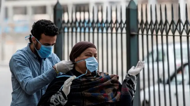 رجل يساعد امرأة في ارتداء القناع