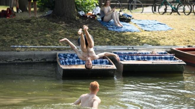 A man performs a back flip from a traditional punt into the River Cam on 25 July, 2019 in Cambridge,