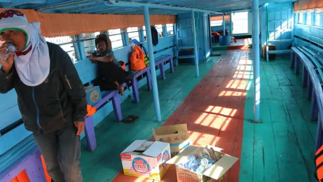 Dua warga berada di dalam kapal motor saat bersandar di Pelabuhan Tigaras untuk membeli bahan kebutuhan, di Simalungun, Sumatera Utara, Rabu (20/06). Kapal kayu tradisional seperti ini merupakan andalan sebagian warga di pelosok Indonesia.