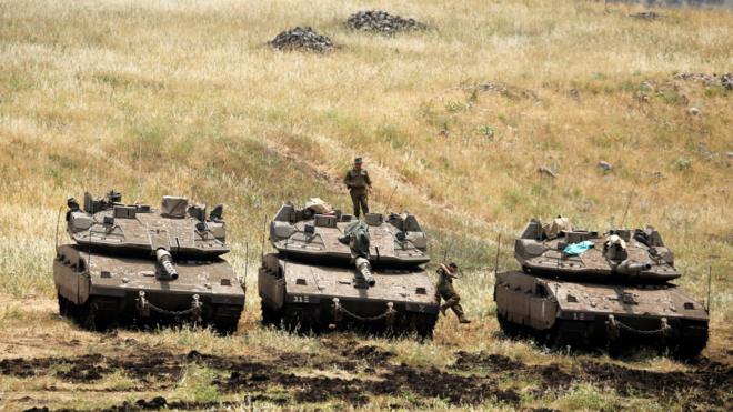 An Israeli soldier stands on a tank as another jumps off it near the Israeli side of the border with Syria in the Israeli-occupied Golan Heights, Israel May 9, 2018.
