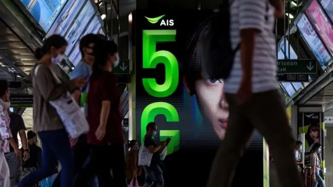 คนเดินผ่านป้ายโฆษณา 5G