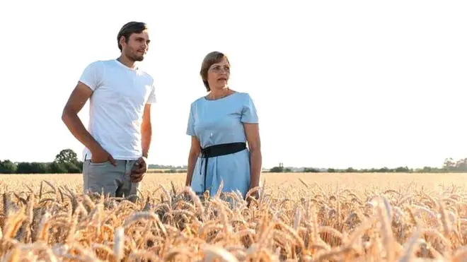 Nadiya and her son Dmytro standing in one of their wheat fields.