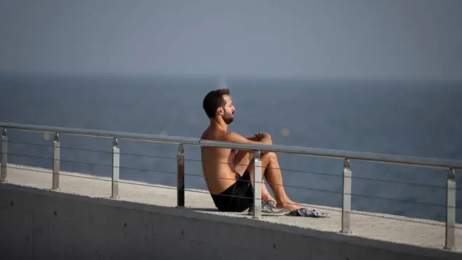 A man enjoys the sun in Barceloneta beach, in Barcelona on October 27, 2022.