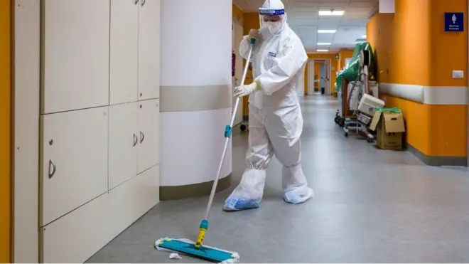 عامل نظافة مزود بمعدات الوقاية الشخصية الكاملة في المستشفى