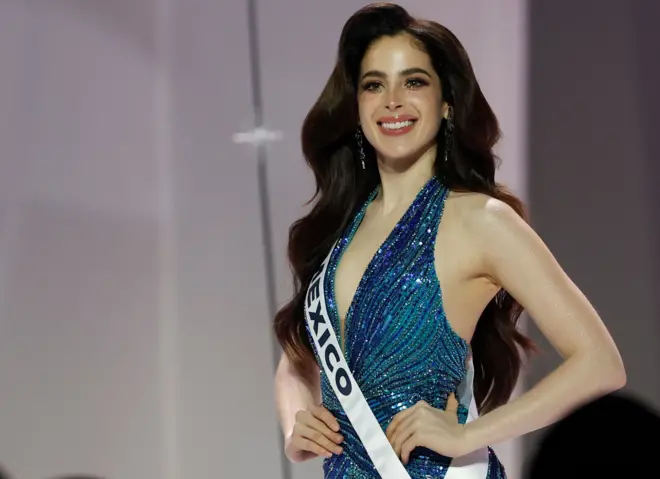 Miss México usando um vestido azul com brilhos e posando com a mão na cintura