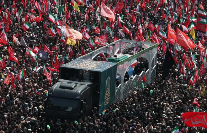 جنازه علی خامنهای در یک لاری قرار دارد و توسط هزاران نفر احاطه شده است.
