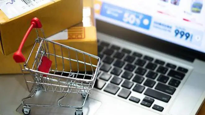 Ноутбук, візок із супермаркета та картонні коробки посилок 