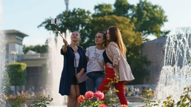 Parkda selfie çubuğu ilə şəkil çəkən insanlar