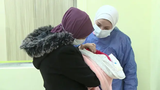 نور والدة التوأمين وهي تحمل واحدة منهما