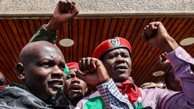 Nicholas Oyoo (ibumoso) na Bob Njagi (iburyo) bazamuye ibipfunsi byabo. Njagi yambaye ingofero itukura - abo bagabo bombi bafite amabendera ya Kenya ku bitugu byabo.