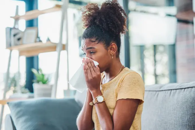Une femme enrhumée en train de se moucher.