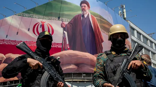 मोजतबा ख़ामेनेई के पोस्टर के साथ ईरानी सुरक्षा गार्ड