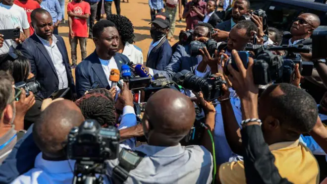 Umurwi w'abanyamakuru benshi mu Rwanda bari mw'ibarabara babaza umukandida, umukuru w'umugambwe 'Democratic Green Party', Frank Habineza, inyuma yo gutorera ku Kimironko i Kigali, kw'igenekerezo rya 15 Mukakaro (7) mu 2024. (Ifoto mbarankuru yo mu bubiko)