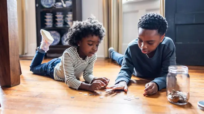 A boy and a girl counting change on floor at home
