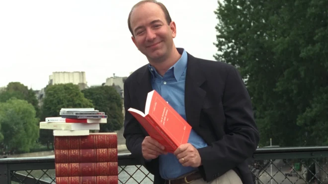 جف بزوس با چند کتاب کنار رودخانه