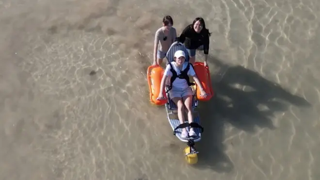 수중 휠체어를 타고 있는 여학생과 이를 끌고 있는 여학생 2명