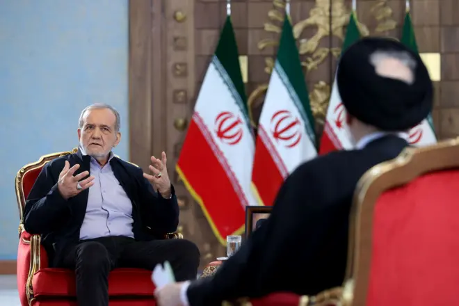 محمدعلی ابطحی از پشت در برابر مسعود پزشکیان، پرچم جمهوری اسلامی ایران در پس زمینه