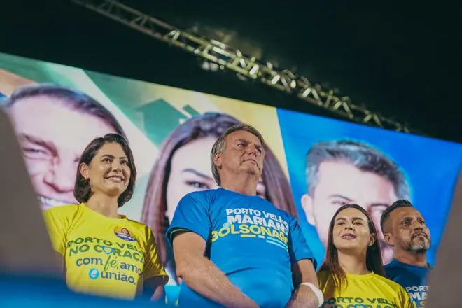 Jair Bolsonaro usando camisa azulum palanquePorto Velho ao ladosua mulher, Michelle Bolsonaro, usando camisa amarela, e da deputada federal e candidata à PrefeituraPorto Velho, Mariana Caravalho,camisa amarela