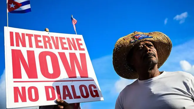 Un hombre sosteniendo un cartel que dice “intervengan ahora” en Miami, Florida.