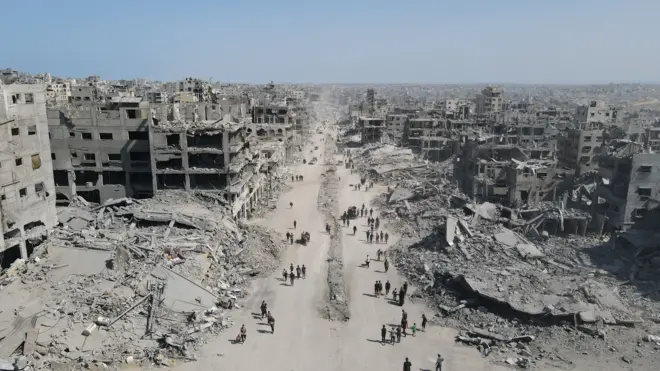 مردم در میان ویرانی‌ها در شهر غزه در شمال نوار غزه در ۱۱ اکتبر ۲۰۲۵ در حال رفت‌وآمد هستند، یک روز پس از آغاز آتش‌بس. 