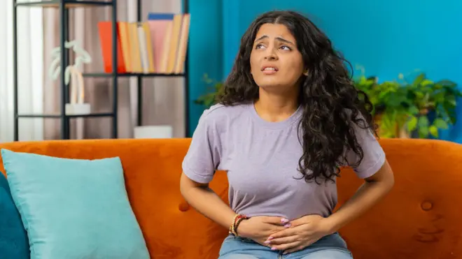 Woman's hands holding an illustration of female reproductive system.