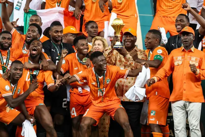 Le président de la Côte d'Ivoire Alassane Ouattara (C) soulève le trophée de la Coupe d'Afrique des Nations sur le podium après la victoire de la Côte d'Ivoire lors de la finale de la Coupe d'Afrique des Nations (CAN) 2024 entre la Côte d'Ivoire et le Nigeria au stade olympique Alassane Ouattara à Ebimpe, Abidjan.