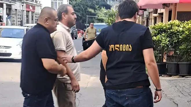 Полицейские ведут журналиста Афгана Садыгова по улице