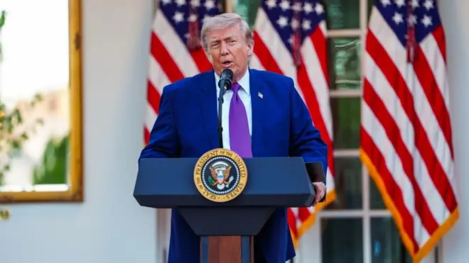 US President Donald Trump speaks from behind a blue podium bearing the US presidential seal, which is outside and positioned in front of three US flags, on 11 May 2026.