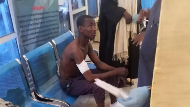 Ọkunrin kan to fori sọta ikọlu ado oloro ologun joko sori aga, bandeji wa ni apa ọtun rẹ. Ko wọ asọ amọ o wọ sokoto, o gbe oju soke lati ba awọn eeyan mẹta to wa niwaju rẹ sọrọ