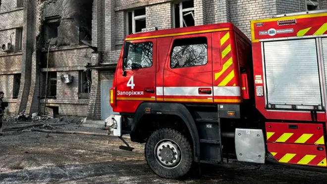 Пожежна машина на фоні палаючого будинку