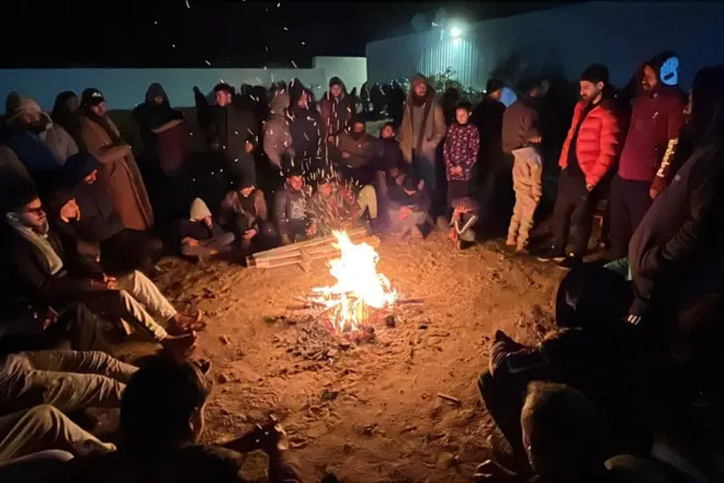 عائلات فلسطينية تدفئ نفسها حول النار، وهي تنتظر خارج المستشفى الأوروبي في خان يونس جنوب قطاع غزة في وقت مبكر من يوم 27 فبراير/شباط 2025، قبل وصول أقاربهم بعد إطلاق سراحهم من قبل إسرائيل. 