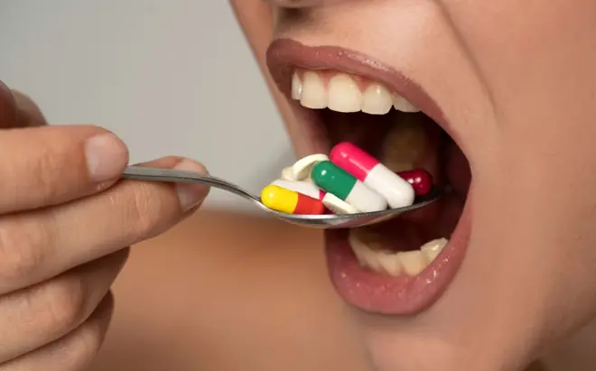 A young woman puts a spoonful of medicine in her mouth