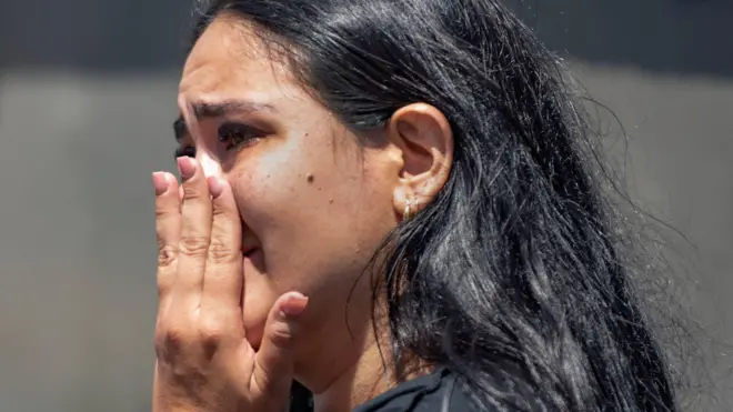 Una mujer reacciona mientras los residentes rebuscan entre los escombros de edificios derrumbados tras un terremoto en Cali.