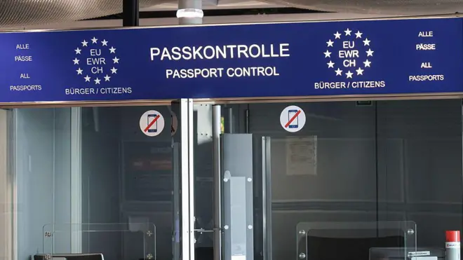 Знаки и стойки пограничного и паспортного контроля в здании терминала после выхода на посадку в международном аэропорту Дюссельдорфа. Знаки пограничного контроля с изображением сотрудника пограничной полиции, европейским флагом со звездами, всеми паспортами и символами ЕС, EWR, CH и текстом на немецком и английском языках расположены перед пунктом пограничного контроля, используемым для вылетов и прилетов из ЕС или стран Шенгенской зоны.