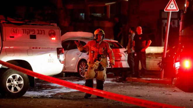 رجل إطفاء يقف في موقع سقوط صاروخ أطلق من قطاع غزة باتجاه إسرائيل في عسقلان. 