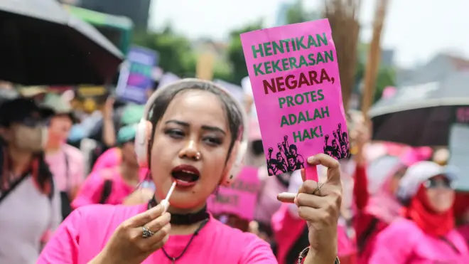 Salah seorang peserta aksi Aliansi Perempuan Indonesia membentangkan poster saat berunjuk rasa di depan kompleks DPR pada Rabu (3/9). 
