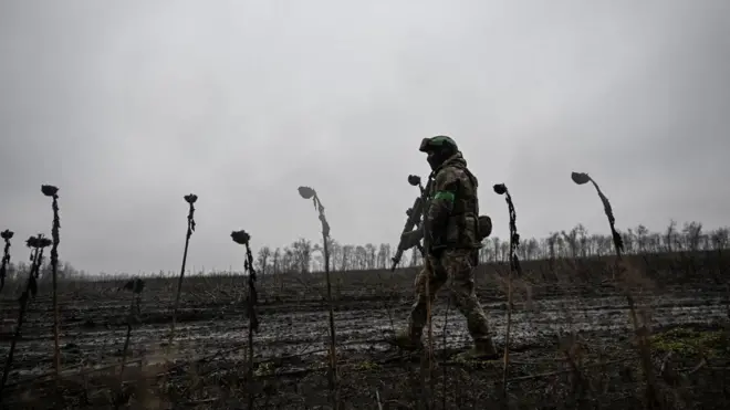 Військовий в формі і з автоматом крокує полем біля Покровська