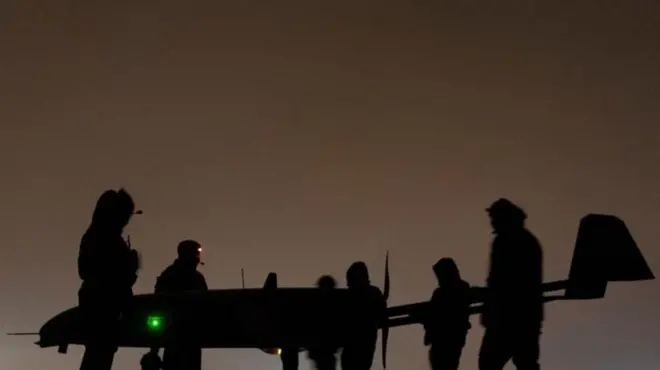 Темні силуети військових поряд з силуетом безпілотника Ан-196 "Лютий"