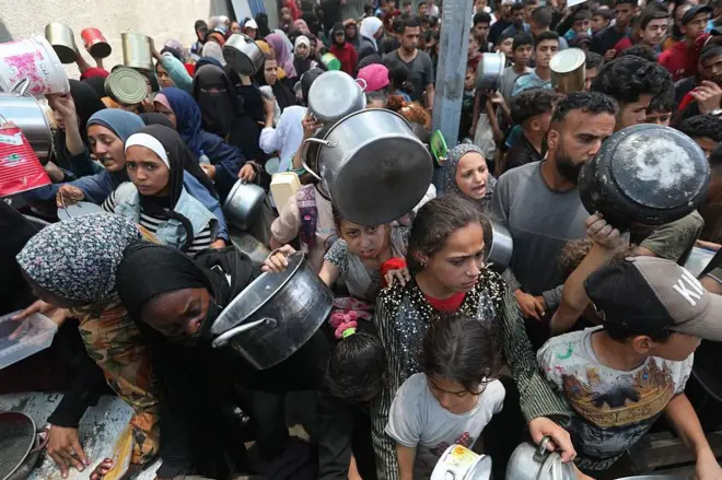 فلسطينيون ينتظرون الحصول على وجبات ساخنة توزعها منظمات خيرية في غزة